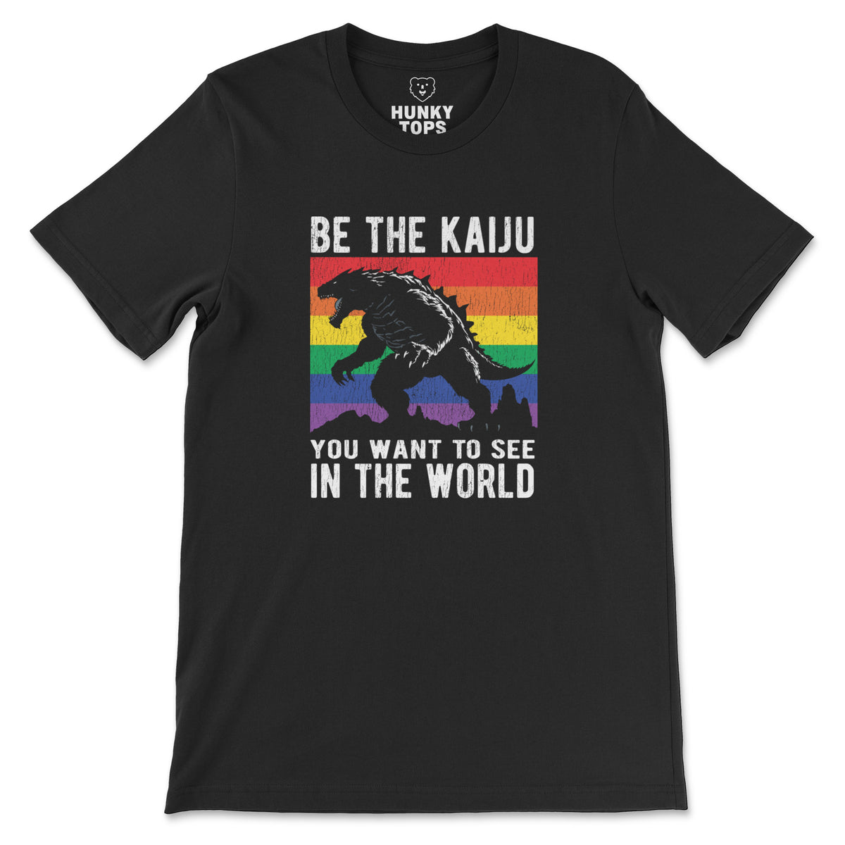 "Be the Kaiju You Want to See in the World" kaiju over a rainbow flag on a black t-shirt, flat lay #color_Black