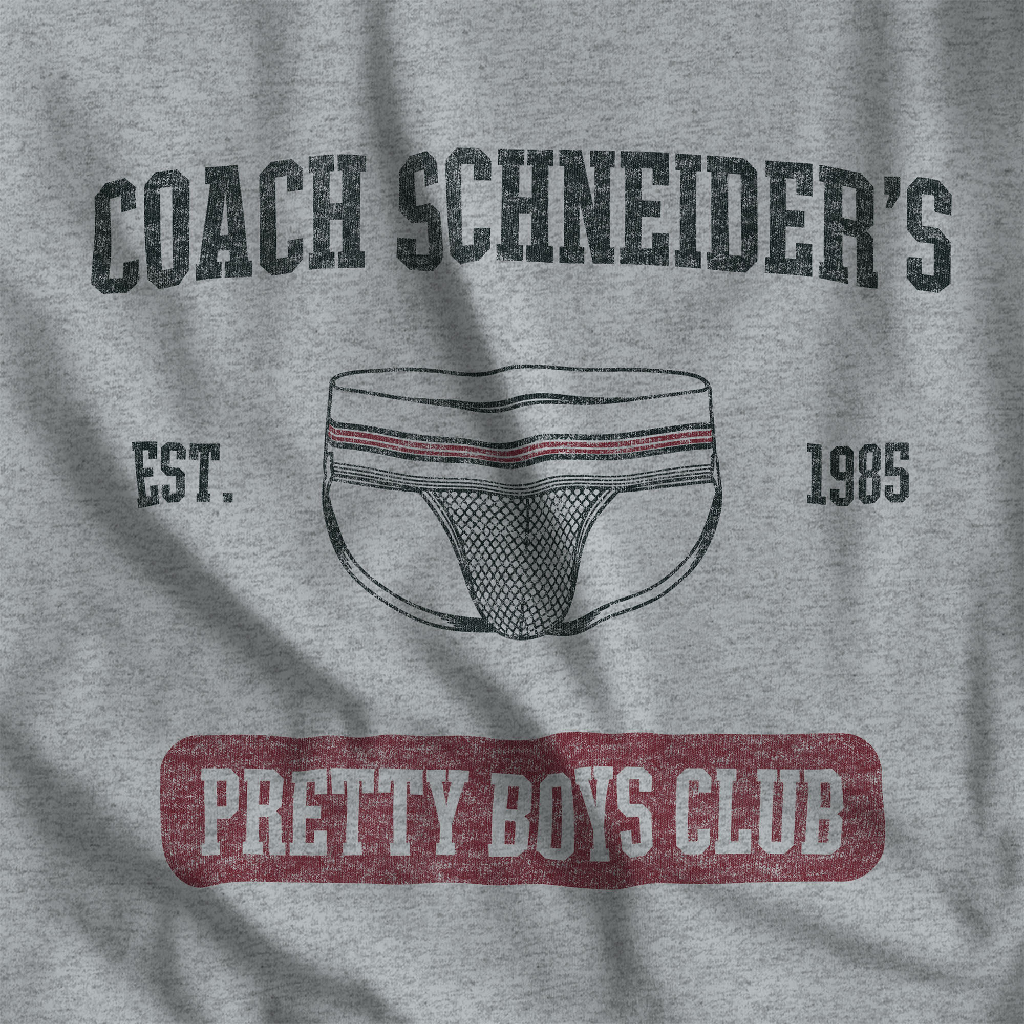 Close up of the distressed collegiate Coach Schneider's Pretty Boys Club print on an Athletic Heather tee #color_Athletic Heather